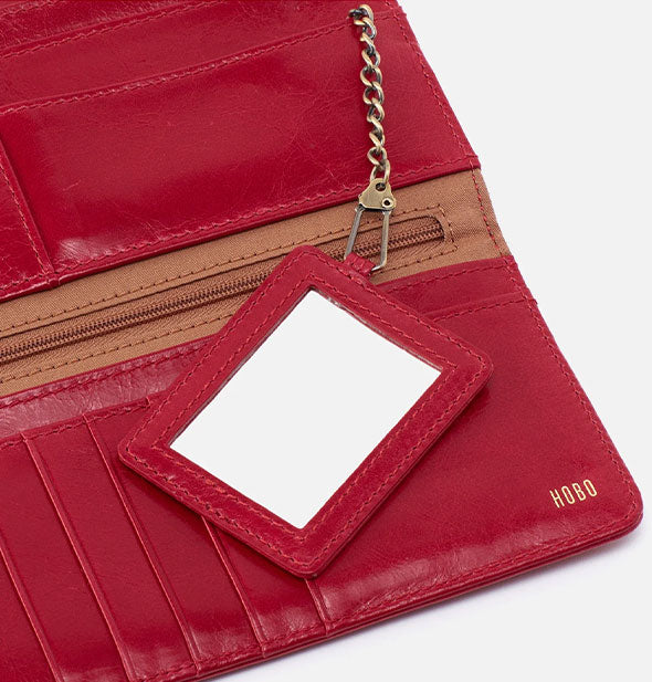 Closeup of red leather wallet interior with mirror attached to an antiqued brass chain