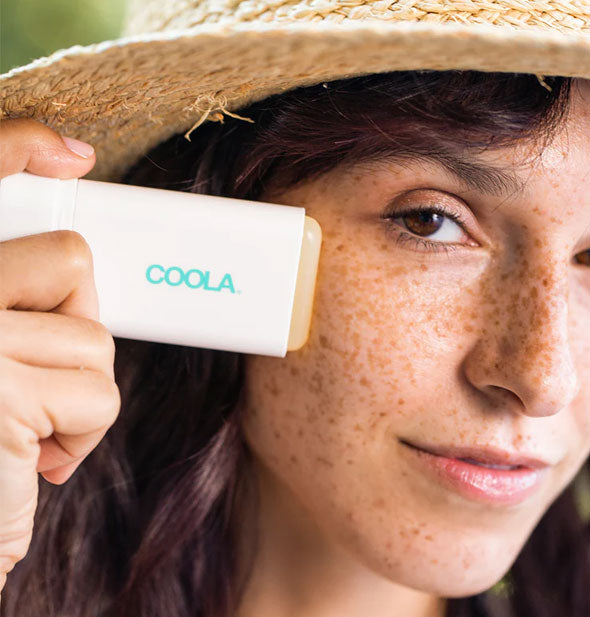 Model applies Coola Classic Sunscreen Stick to cheek