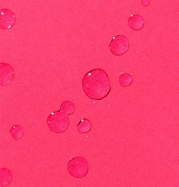 Clear droplets of Clear Start Clarifying Bacne Spray on a dark pink surface