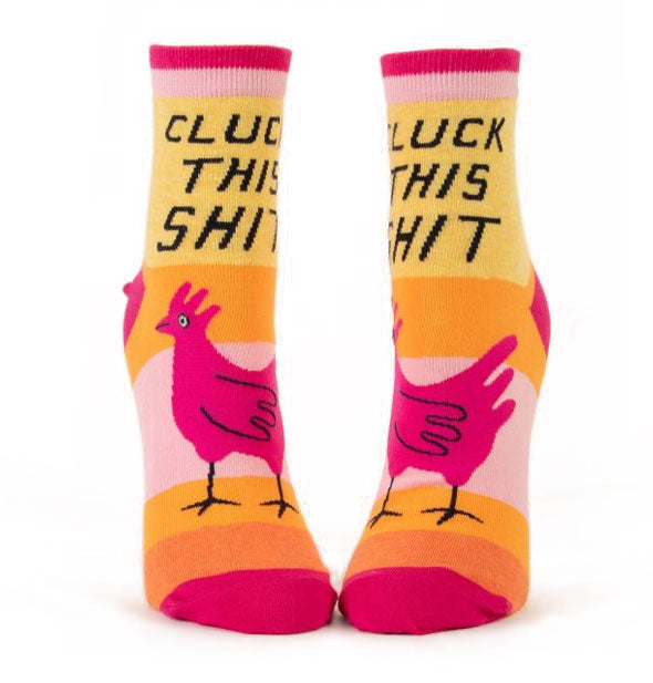 Pair of striped pink, orange, and yellow socks with designs of chickens each say, "Cluck This Shit" in black lettering on ankles