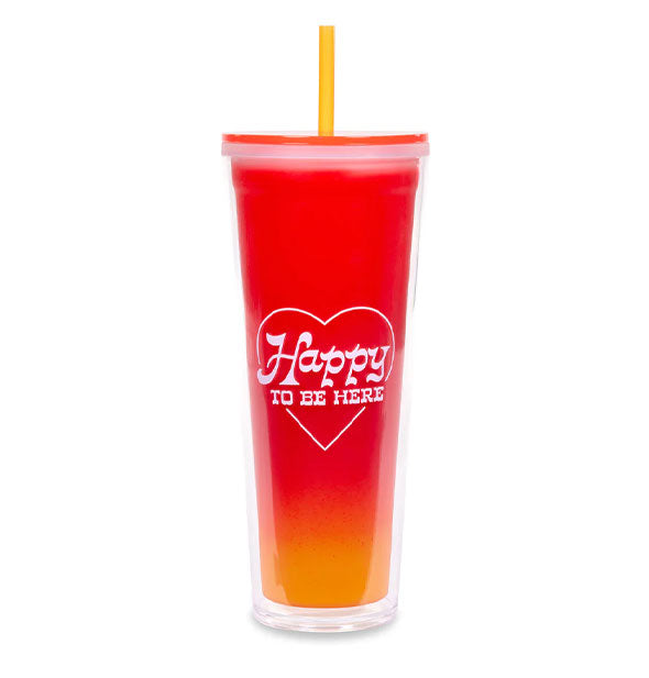 Red-to-orange ombre drink tumbler with yellow straw says, "Happy to be here" in white lettering inside a white heart outline