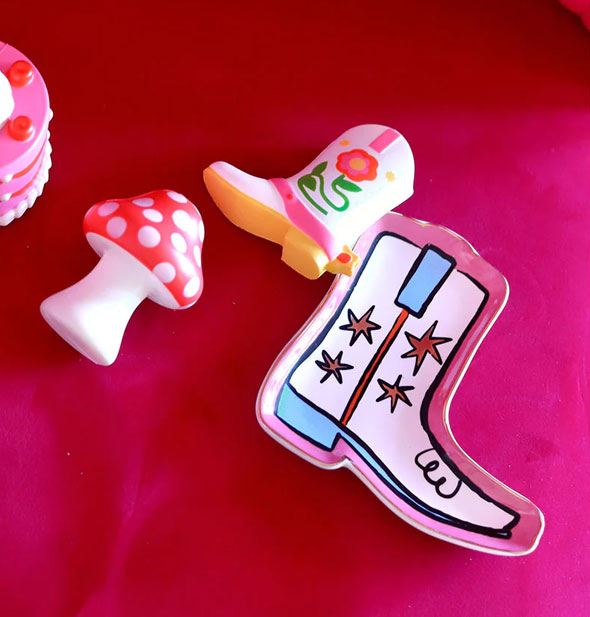 Cowboy boot trinket tray rests on a pink cloth surface with foam cake, mushroom, and cowboy boot toys