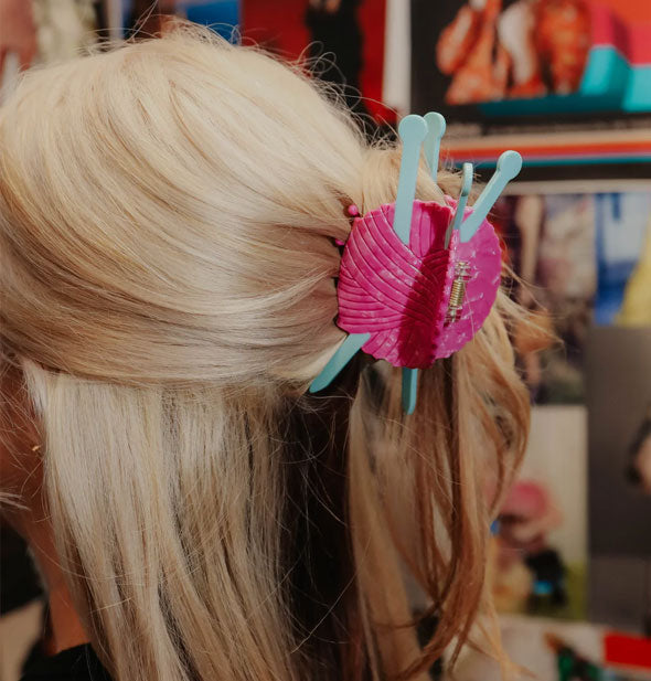 Model wears a yarn ball and knitting needles claw clip in a half-up hairstyle