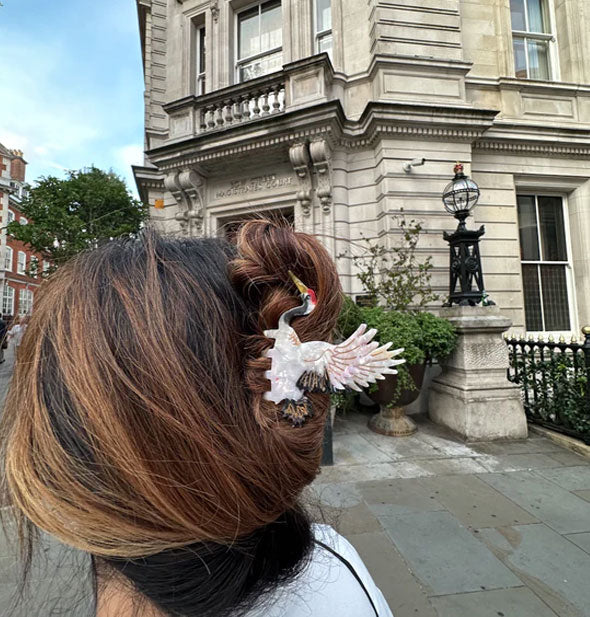 Model wears a crane claw clip in front of a Neoclassical style governmental building