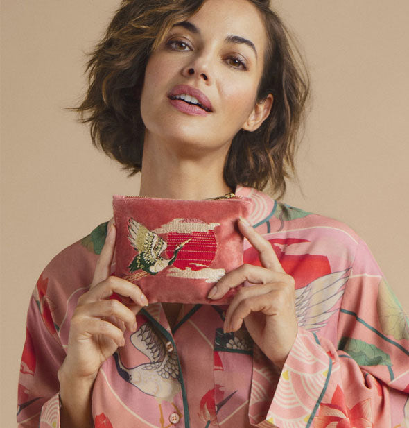 Model holds a pink velvet crane pouch in both hands