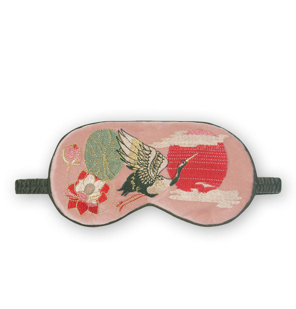 Plush pink sleep mask with green piping and elastic band features embroidered design of flowers and a crane in flight in front of a red sun