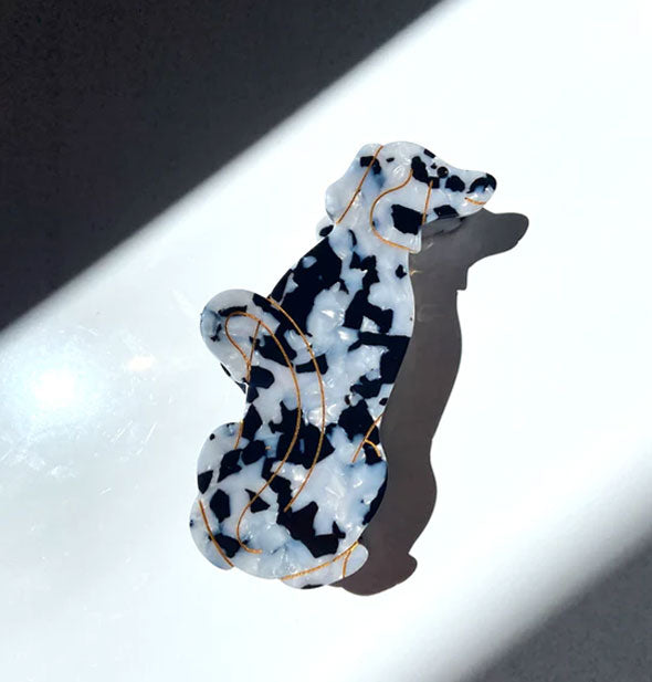 Black and white hair claw designed and painted to resemble a Dalmatian dog with gold accent lines