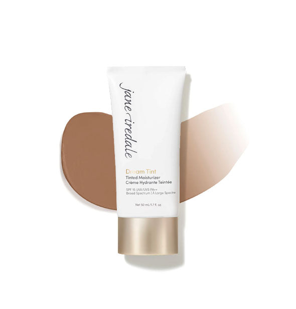 White and gold tube of Jane Iredale Dream Tint Tinted Moisturizer with enlarged smeared product application behind in shade Dark