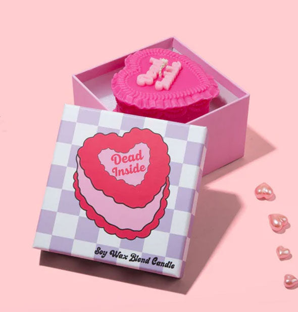 Dead Inside heart-shaped cake candle in box with checkered lid removed is staged with several pink heart-shaped bath oil beads