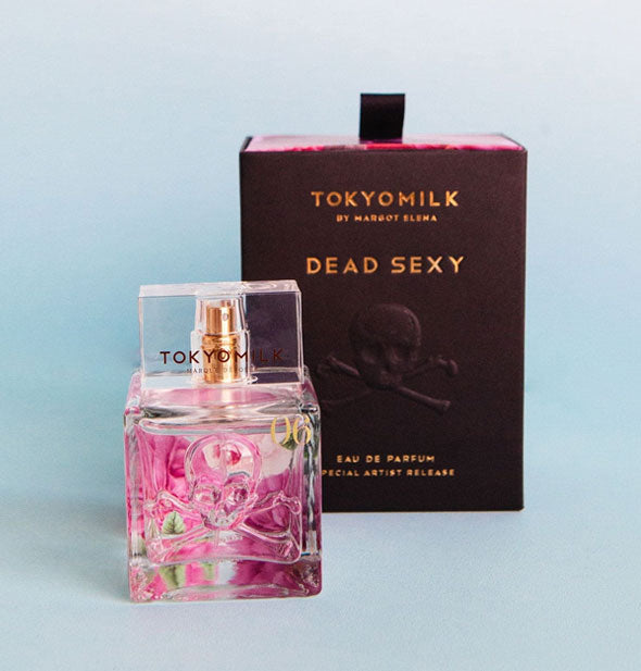 Square glass pink floral perfume bottle with embossed skull and crossbones design sits in front of a dark TokyoMilk Dead Sexy Eau de Parfum box