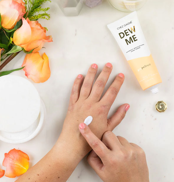 Model applies Dew Me moisturizer to back of hand with fingertip