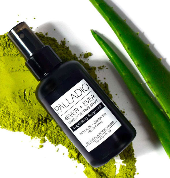 Bottle of Palladio 4Ever + Ever Makeup Setting Spray rests on a pile of green tea powder next to green sprigs of aloe