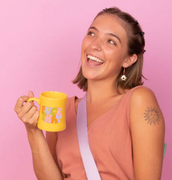 Smiling model holds a yellow Fuck That diner mug by the handle