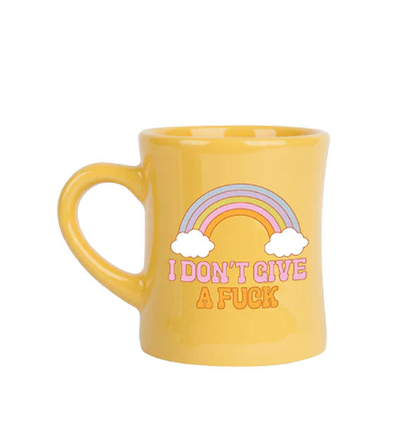 Yellow diner mug says, "I don't give a fuck" in pink and orange lettering below a rainbow and white clouds graphic