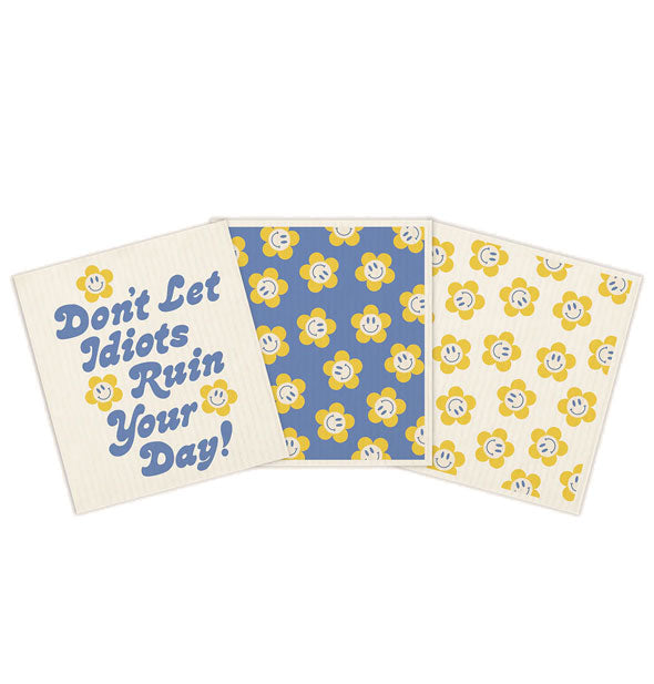 Three dish towels in a set feature a "Don't Let Idiots Ruin Your Day!" design and two with smiley face flower print in blue and yellow