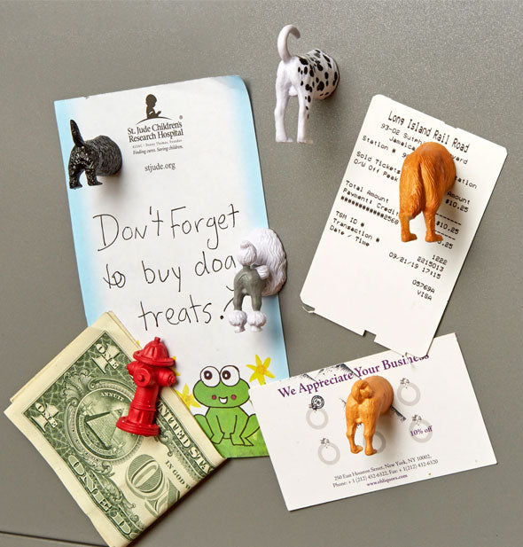 Dog butts and fire hydrant magnets set hold a memo, business card, ticket, and dollar bill to a metal surface