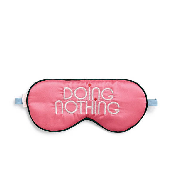 Pink satin sleep mask with dark piping and blue elastic is embroidered in white and red with the words, "Doing Nothing"