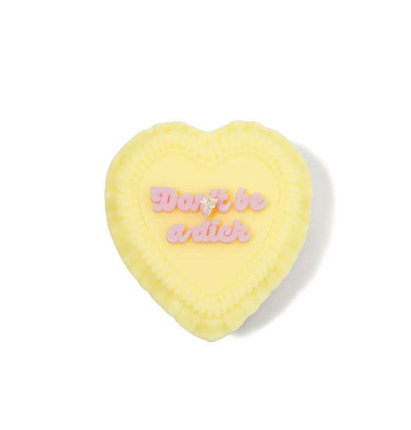 Yellow heart-shaped candle designed to resemble a frosted cake with the words, "Don't be a dick" on top in pink script lettering