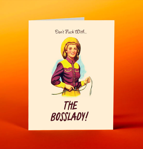 Greeting card on red and orange background says, "Don't Fuck With..." at the top above an illustration of a cowgirl holding a lasso, and, "The Bosslady!" at the bottom