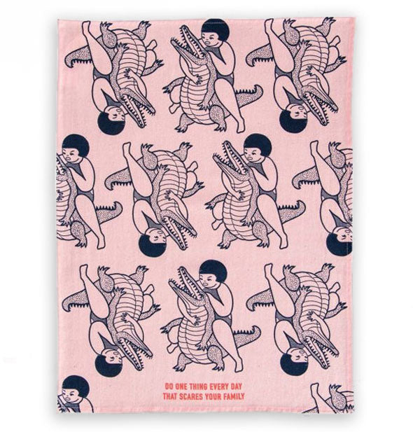 Pink dish towel with repeating illustration of girl wrestling a crocodile says, "Do one thing every day that scares your family"