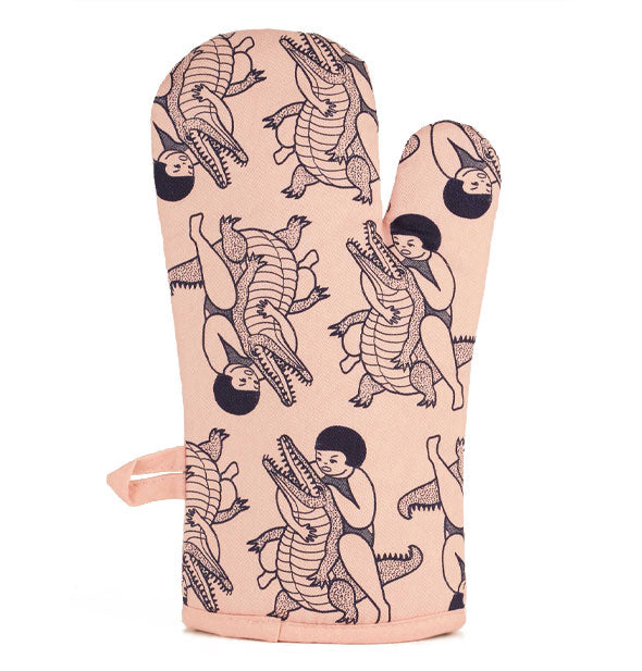 Light peachy-pink oven mitt features a repeated illustration of a girl wrestling an alligator in black