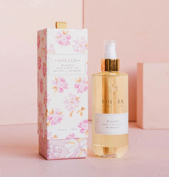 Clear glass bottle of Lolllia Breathe Peony & White Lily Dry Body Oil next to decorative pink and white floral print box