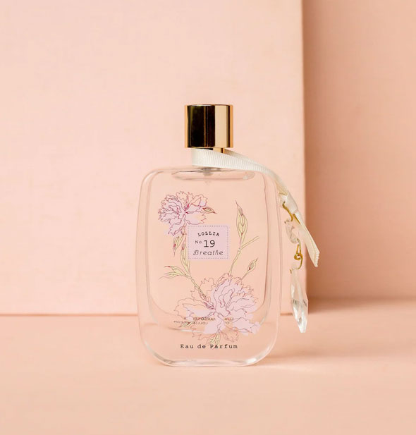 Clear glass bottle of Lollia No. 19 Breathe Eau de Parfum with delicate floral design and white ribbon hanging from the neck of a gold spray nozzle