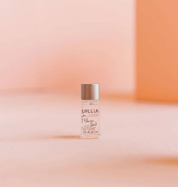 Small rectangular glass Lollia Classic Petal In Love Eau de Parfum bottle with silver cap against a pink backdrop