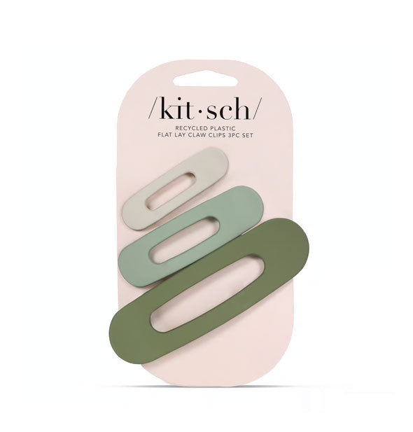 Three ovoid open-shape matte hair clips in neutral green shades are affixed to a pink Kitsch product card