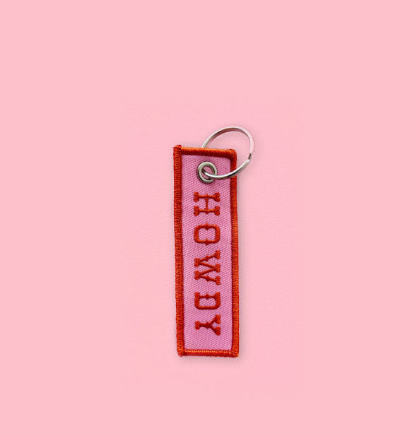 Rectangular pink embroidered keychain tab with red border and lettering that says "Howdy" in Old West-style lettering