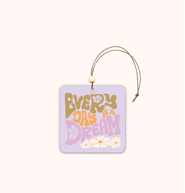 Square purple car air freshener tag with rounded corners says, "Every Day Is a Dream" in psychedelic lettering accented by daisies and hangs from a brown string with white bead