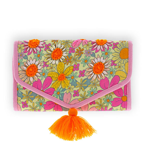 Brightly colored, rectangular floral print clutch with pink piping and orange pompom on its pointed flap