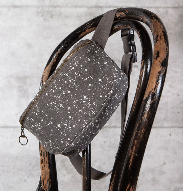 Starry sky hip bag is slung over the back of a distressed wooden chair