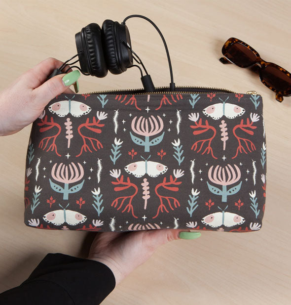 Model removes a pair of headphones from a Far and Away Large Cosmetic Bag