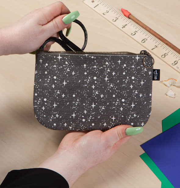 Model pulls scissors from a starry sky pouch