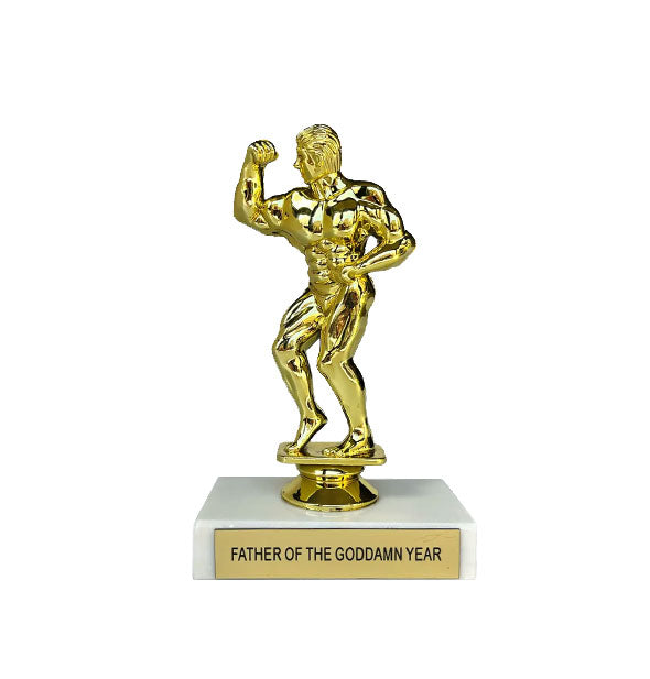 Trophy with figurine of a flexing muscle man in gold atop a white rectangular base that reads, "Father of the Goddamn Year" on a gold placard