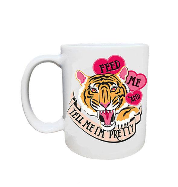 White coffee mug features a roaring tiger's face and paw with flames reflected in her eyes flanked by pink hearts and a banner that read, "Feed me and tell me I'm pretty"