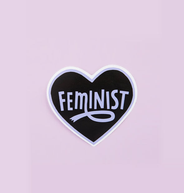 Black heart-shaped sticker with a purple and white edge says, "Feminist" in purple lettering