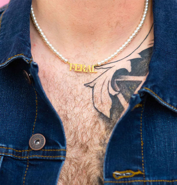 Model with chest tattoo in a dark denim jacket wears the Feral Pearl Necklace