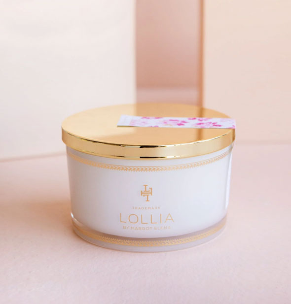 Tub of Lollia bath salts with shiny gold lid secured by a pink floral-patterned sticker label