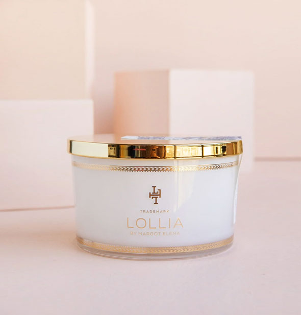 White tub of Lollia bath salts features a shiny gold lid and design details