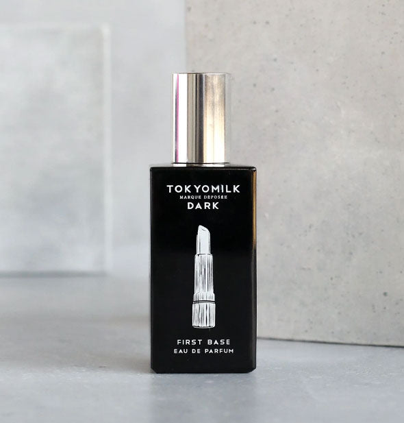Rectangular black bottle of TokyoMilk First Base Eau de Parfum with silver cap and white lipstick graphic