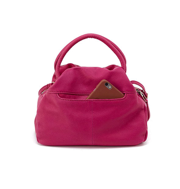 Reverse side of dark pink leather satchel bag reveals an exterior slip pocket out of which a phone is partially emerging