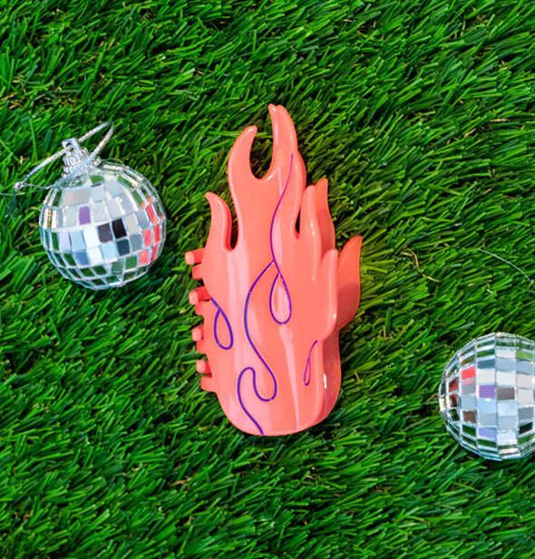 Coral flames hair claw clip on green astroturf staged with two mini disco balls