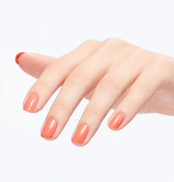 Model's fingernails are painted with coral polish