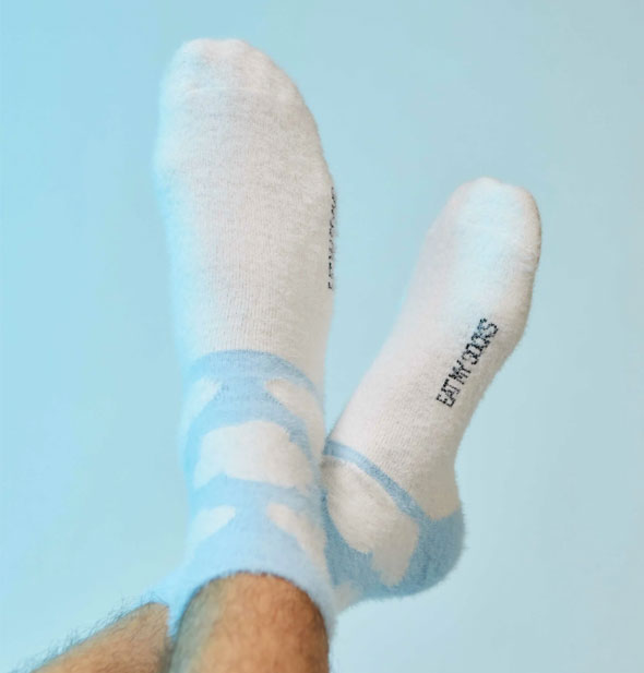 Model wears blue and white cloud print socks with Eat My Socks logo