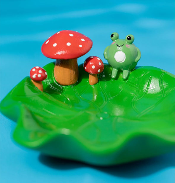 Closeup of frog and mushrooms details on green lily pad ashtray