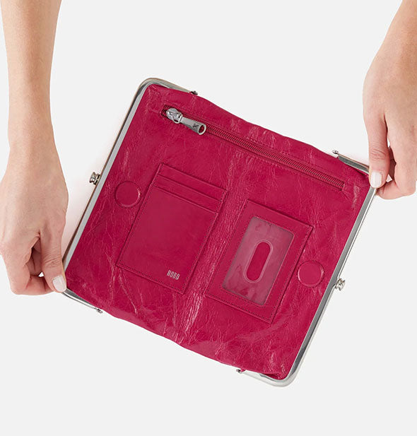 Model's hands hold open a fuchsia leather wallet to reveal slots and pocket storage inside