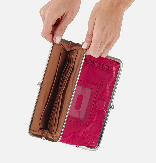 Model's hands hold open a pocket of a fuchsia leather wallet to reveal a brown interior with card slots