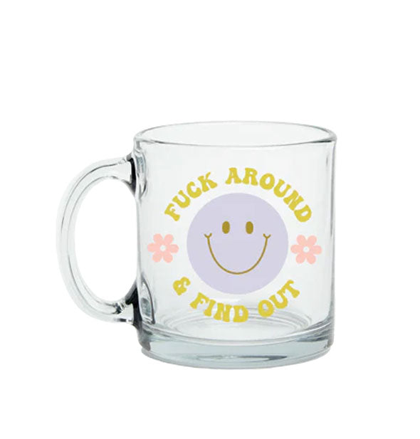 Clear glass mug with blue smiley face says, "Fuck around & find out" in greenish-yellow retro-style lettering accented with two pink daisies